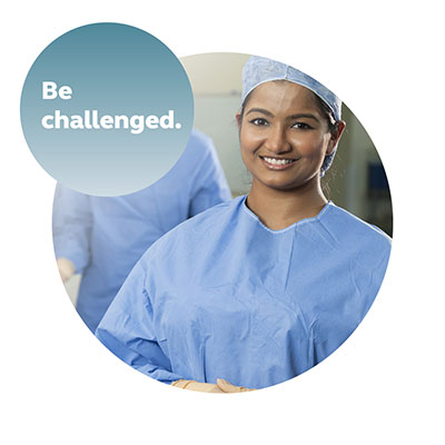A smiling young graduate nurse in blue scrubs.