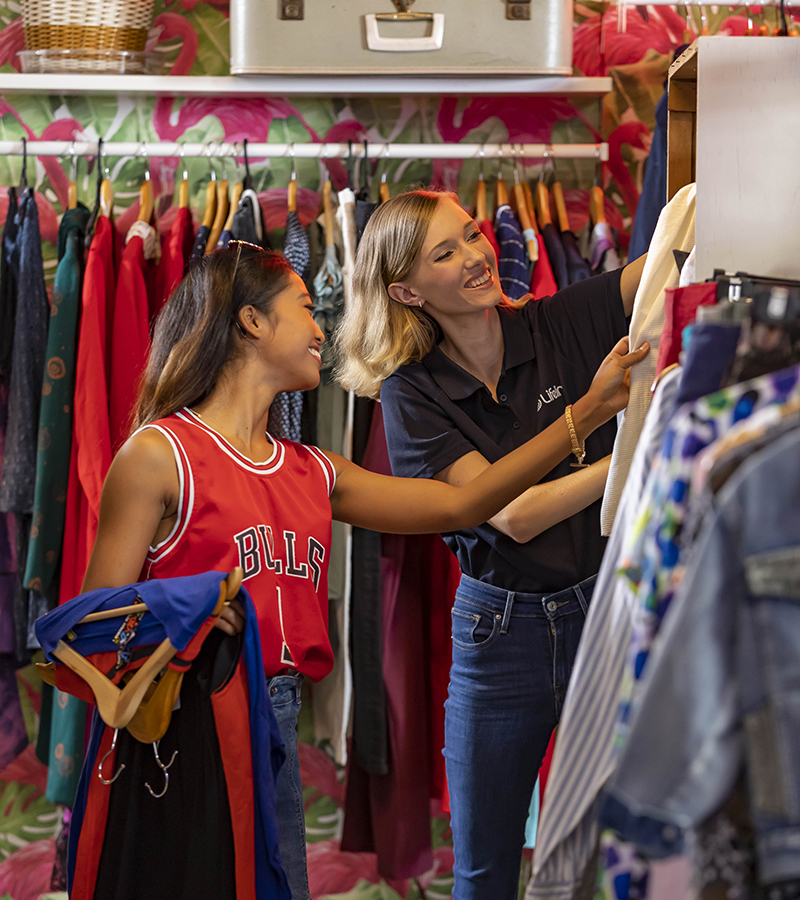 A female Lifeline volunteer helps a female customer choose clothes in a Lifeline shop
