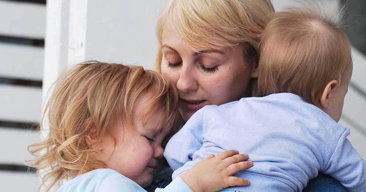 A mum holds her two young children close.