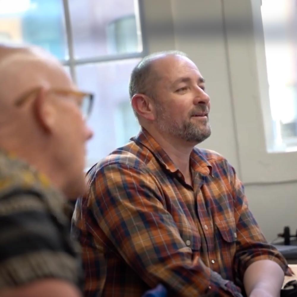Lifeline training recipient sitting at desk with colleague looking at a computer monitor