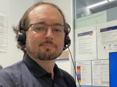 Dominic Owen with a headset sitting in a call centre