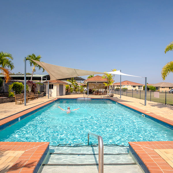 A lady swimming in a large pool with sparkling blue water