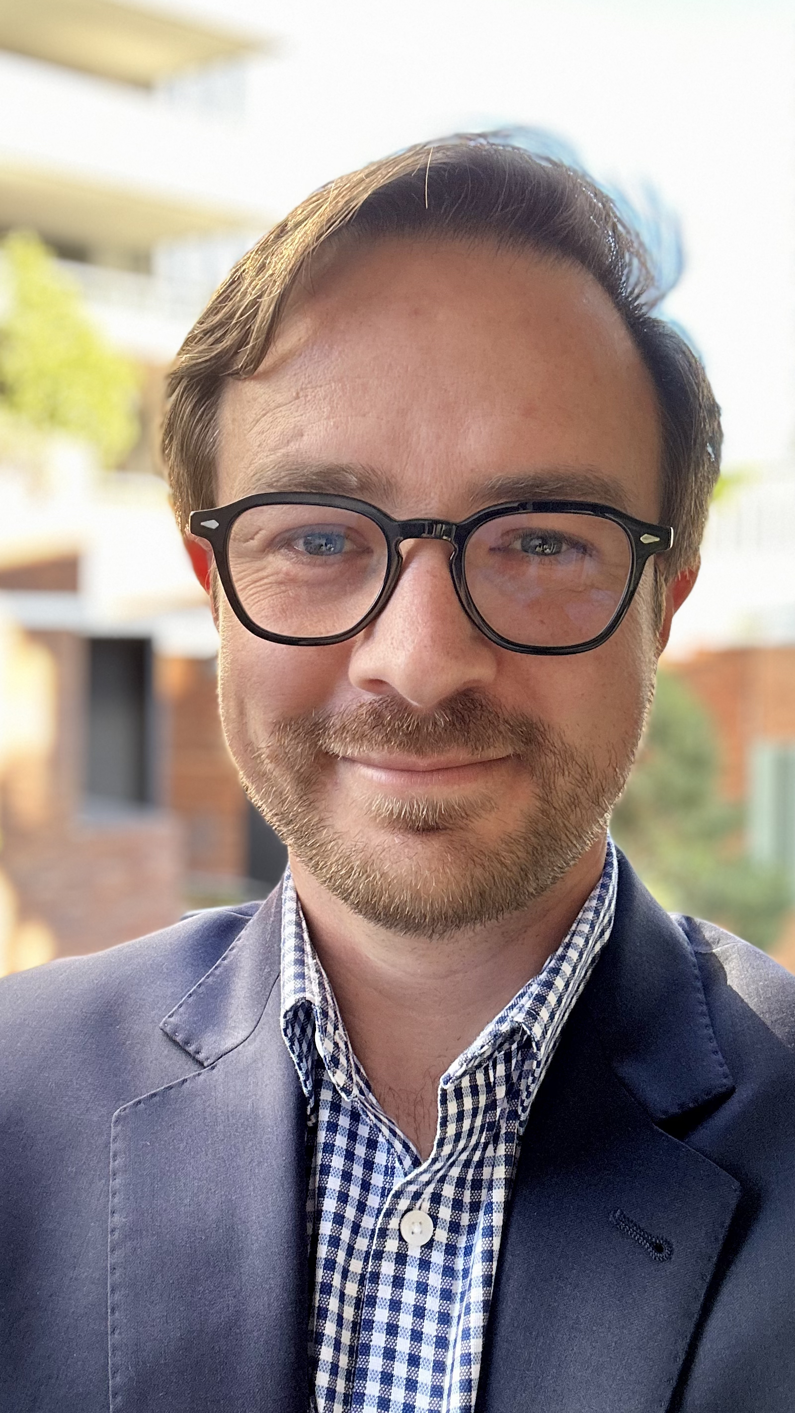 Dr Rhett Morton with a short beard, blue jacket and glasses