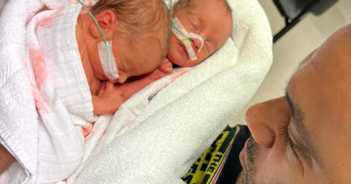 Father holding and looking at newborn twins