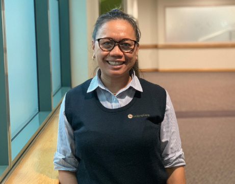 A healthcare worker smiles in a hospital corridor